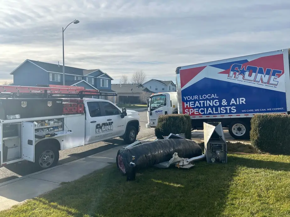 A-One service truck and box truck at a home during a system changeout, with the old ductwork and furnace on the lawn