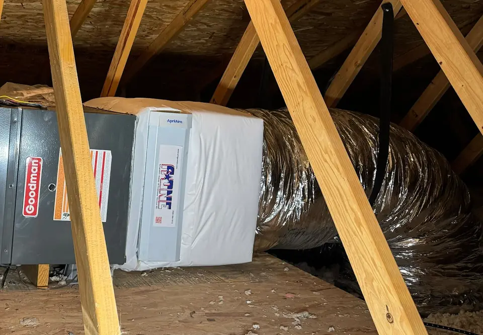 Media air filter cabinet with an A-One service sticker feeding an insulated duct run in an attic